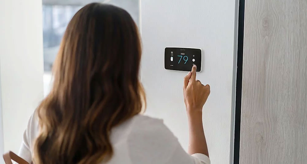 Woman adjusting temprature on smart thermostat